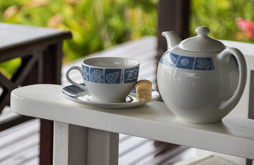 Porcelain coffee cup with pot.
Breakfast with coffee on the terrace. Blurred background.