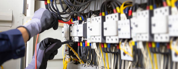 Electrician engineer tests electrical installations and wires on relay protection system. Adjustment of scheme of automation and control of electrical equipment.