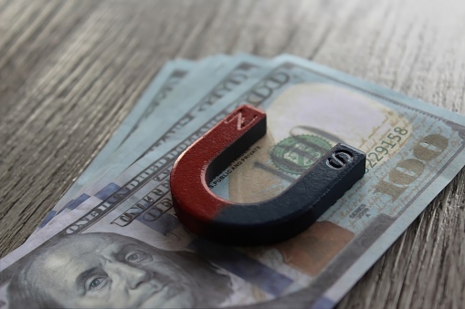 Selective focus image of magnet on top of money. Business and financial concept.