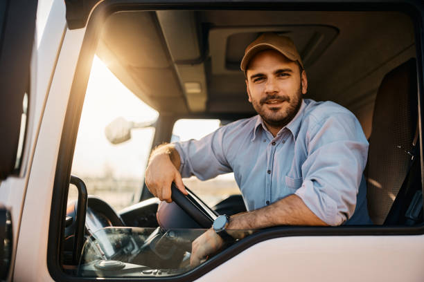 Professional driver sitting in truck cabin and looking at camera. stock photo
