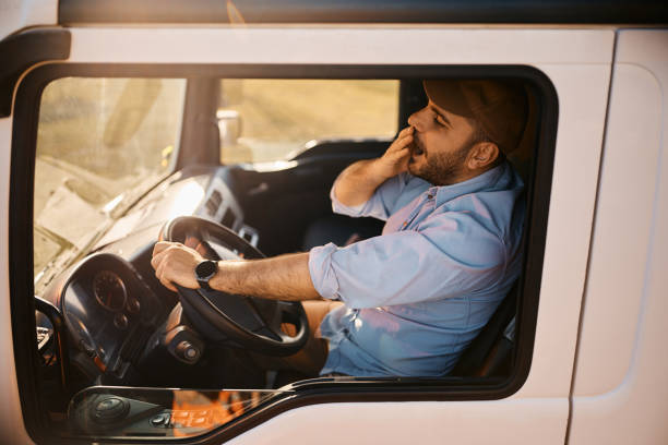 conductor de camión exhausto bostezando mientras conduce su camión. - truck driver truck driver driving fotografías e imágenes de stock