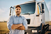 Happy truck driver with crossed arms looking at camera.