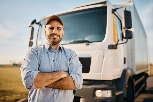 Photo of Happy truck driver with crossed arms looking at camera.