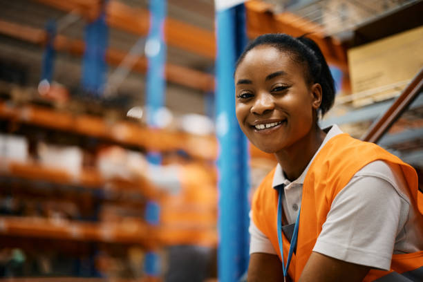 happy black female worker at distribution warehouse looking at camera. - warehouse worker imagens e fotografias de stock