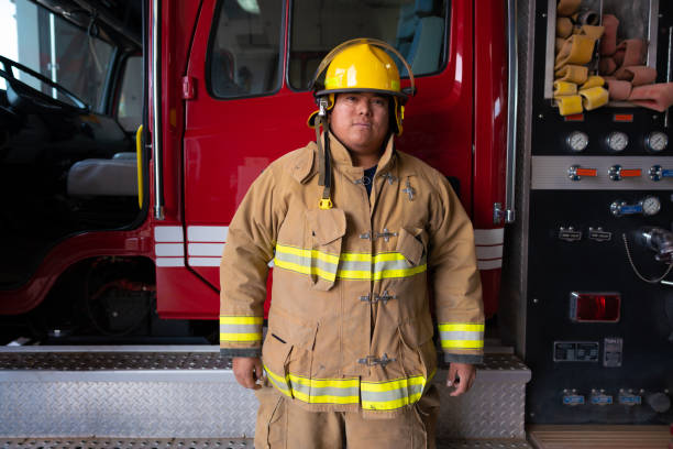istock Firefighter wearing protection suit standing in front of a fire engine truck 1396607506