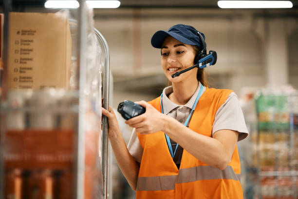 lavoratrice felice che utilizza il lettore di codici a barre durante la scansione dei pacchi in un magazzino. - warehouse bar code reader manual worker working foto e immagini stock