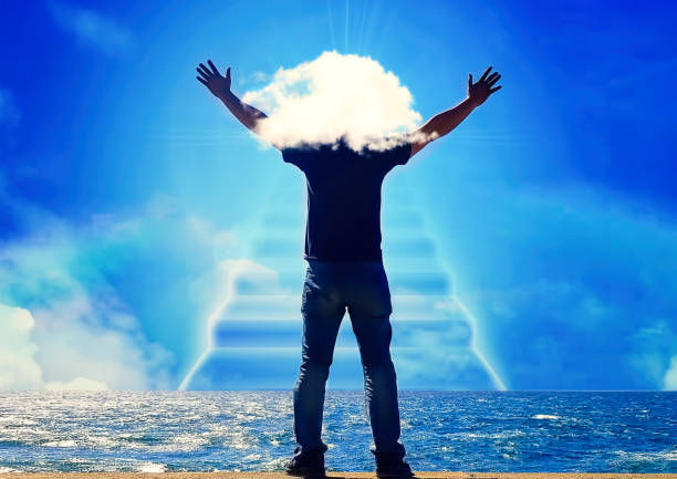 Back view of a man praying with his hands open in the sky