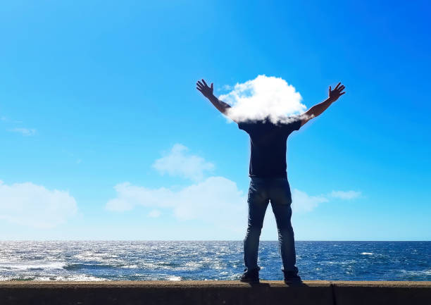 Back view of a man praying with his hands open in the sky