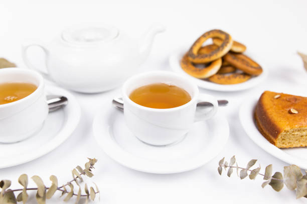 a white tea set with teapot tea and saucers and pie for breakfast
