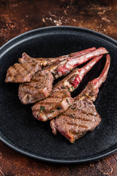 istock BBQ Grilled lamb chops steaks in a plate. Dark background. Top view 1396611590