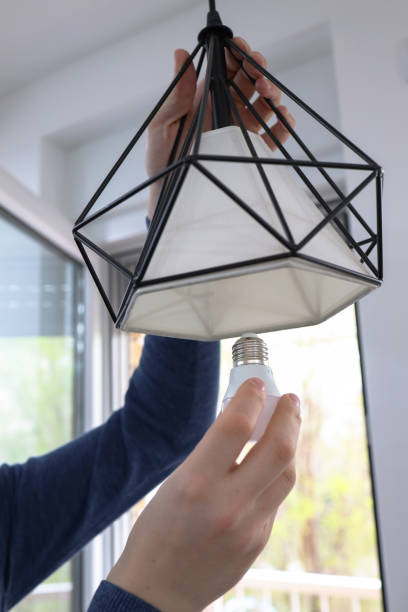 istock A hand changes a light bulb in a stylish loft lamp at home. 1396611596