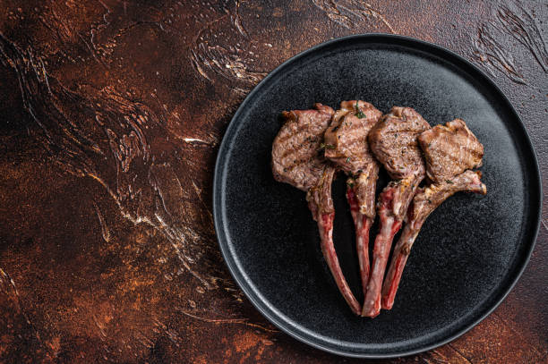 BBQ Grilled lamb chops steaks in a plate. Dark background. Top view. Copy space