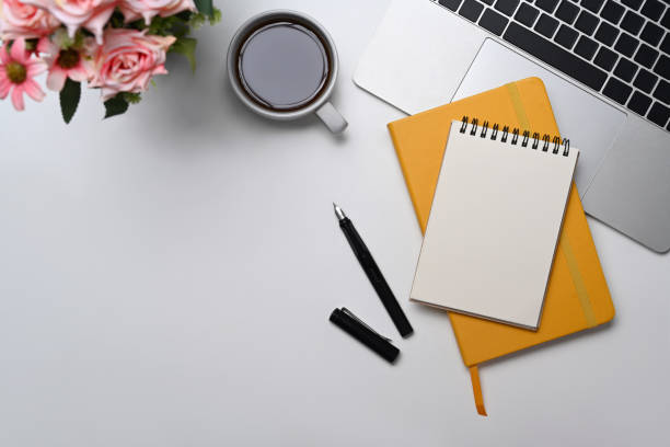 istock Blank notepad, coffee cup and computer laptop on white office desk. Flat lay. 1396611869