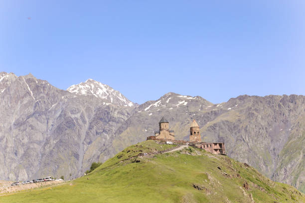 die dreifaltigkeitskirche in gergeti befindet sich am fuße von kazbek entlang der georgischen militärautobahn im georgischen dorf gergeti, direkt über dem dorf stepantsminda - kazbek stock-fotos und bilder