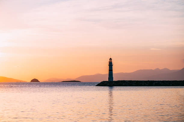 côte égéenne et phare au coucher du soleil - mer egee photos et images de collection