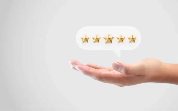 Photo of Hand review customer feedback rating gold star service best product quality of positive ranking evaluation rate or user experience good satisfaction and excellent business success on vote background.