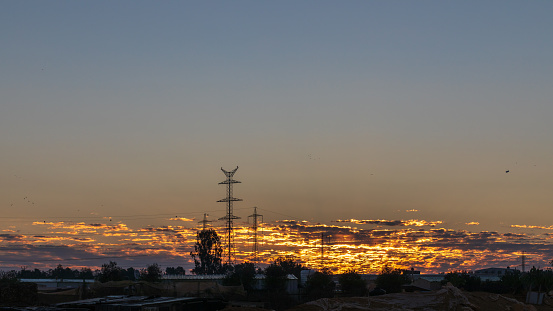 Power lines in distant hills against golden sky background