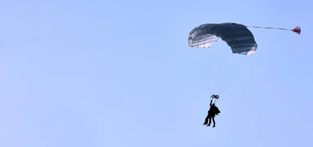 istock A skydiver with a white parachute canopy against a blue sky and white clouds, close-up. 1396617175