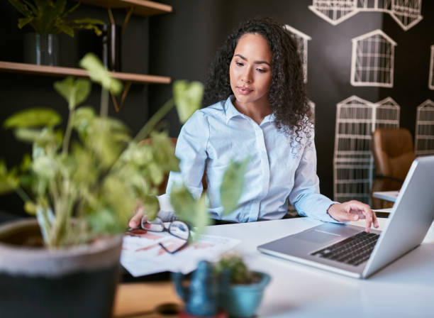 istock Young mixed race business woman thinking and reading paperwork while using a laptop in an office. Ambitious hispanic entrepreneur using documents and a computer to plan for her startup as a freelancer 1396617303