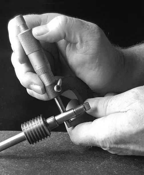 Hands measuring precision part with micrometer.