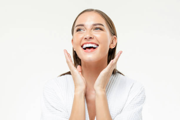 Happy woman with smooth skin Optimistic female with clean face skin looking away with smile on white background with raised hands in light studio spa lady stock pictures, royalty-free photos & images