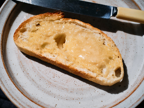 Slice of San Francisco style sourdough bread toasted spread with melted butter and honey.