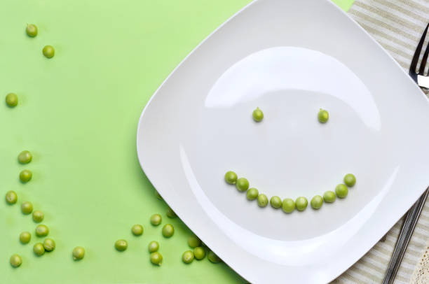 Smiling Green Peas on the Plate Smiling Green Peas on the Plate/Studio Shot happy green peas stock pictures, royalty-free photos & images