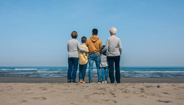 Unrecognizable people in the beach backwards watching the sea stock photo