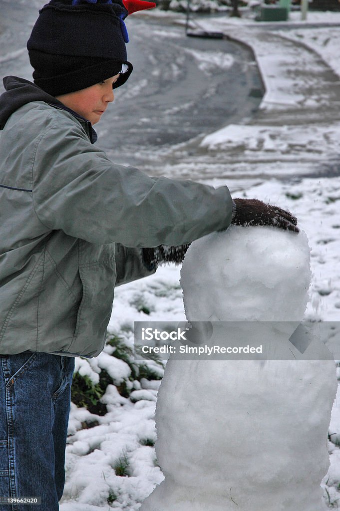 Intense concentration Young boy concentrating as he builds his snowman. Art And Craft Stock Photo