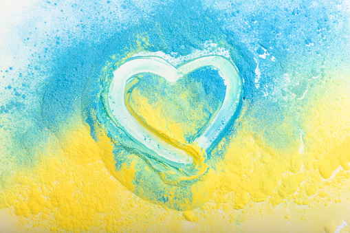 Ukrainian flag in the shape of a heart, the concept of peace in Ukraine. Powder paint Holi. Yellow and blue.