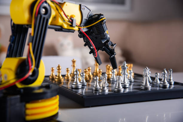 Closeup yellow robot arm playing move chess on chessboard stock photo