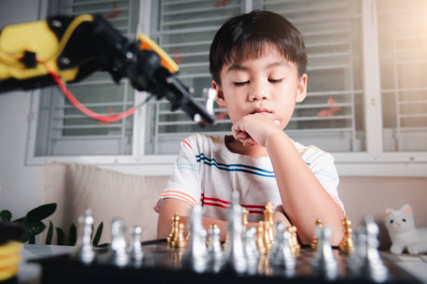 istock Asian little boy thinking and wait robot arm playing chess 1396627771