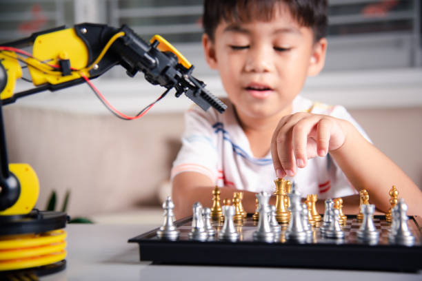istock Asian little boy is playing chess with robot machine arm 1396627776