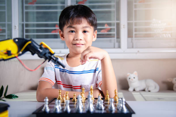 istock Asian little boy is playing chess with robot machine arm 1396627785