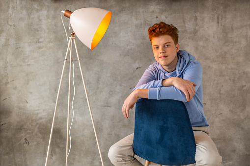 Portrait of Caucasian teenage redhead boy sitting on the chair