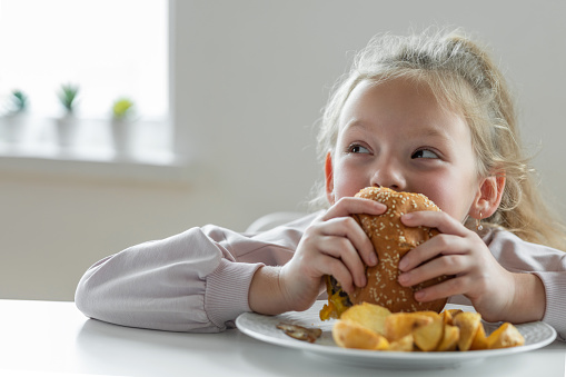 Little girl eating a big burger