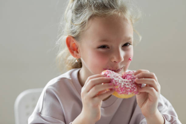 istock Girl eating unhealthy donut 1396630106