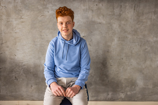 Portrait of Caucasian teenage redhead boy sitting on the chair