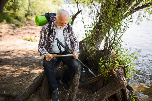 istock Senior hiker sitting looking at hiking map and navigational compass 1396631095