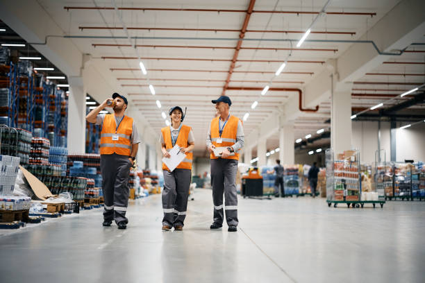 istock Group of happy warehouse workers walking through distribution storage compartment. 1396631493