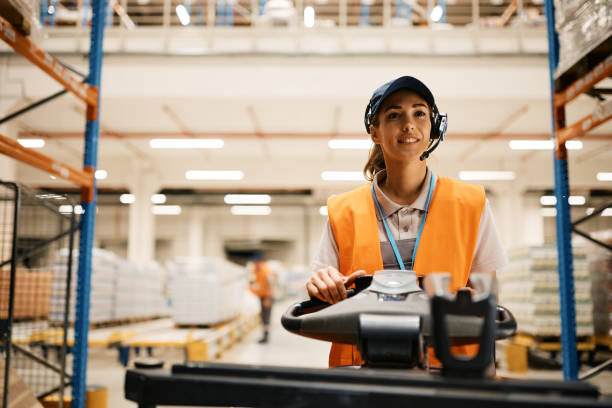 istock Young female worker driving pallet jack while working at distribution warehouse. 1396631642