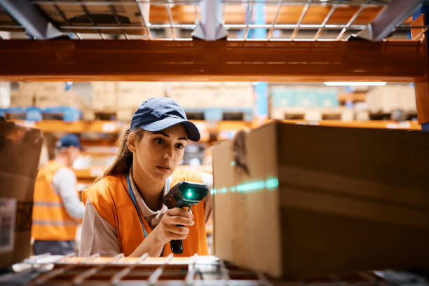 Female warehouse worker scanning packages at storage compartment.
