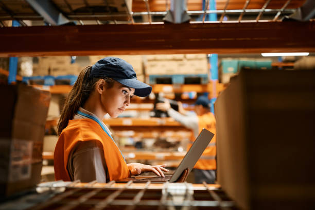 female worker using laptop while working at distribution warehouse. - warehouse worker imagens e fotografias de stock