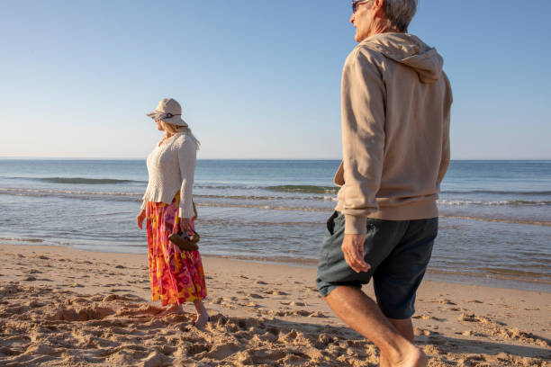 istock Mature couple walk, barefoot, down sandy beach 1396636515