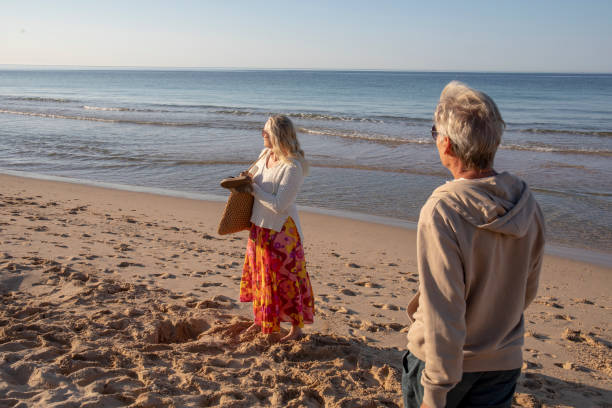 istock Mature couple walk, barefoot, down sandy beach 1396636627