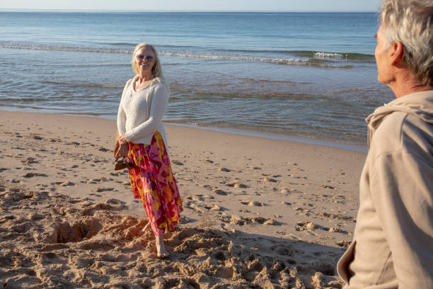 istock Mature couple walk, barefoot, down sandy beach 1396636673