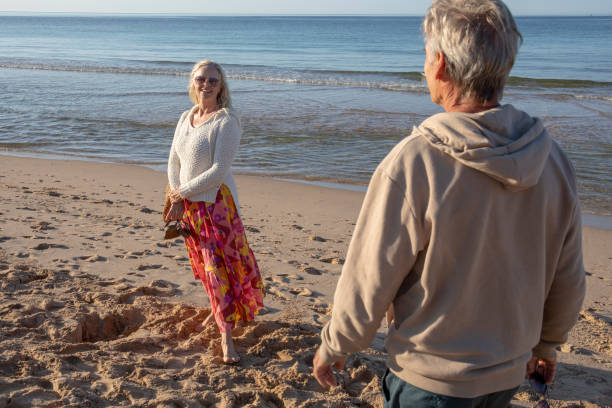 istock Mature couple walk, barefoot, down sandy beach 1396636712