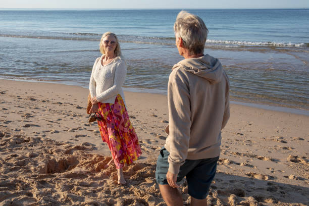 istock Mature couple walk, barefoot, down sandy beach 1396636713