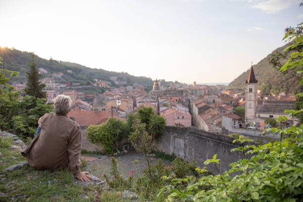 istock Man relaxes at viewpoint, above medieval village 1396637524