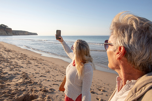 They take selfies on cellphone, by the Atlantic Ocean